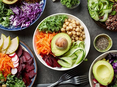 Reich gedeckter Tisch mit vielen Veganen Lebensmitteln, wie Avocado, Karotten, Salat, Rote Beete und vieles mehr.