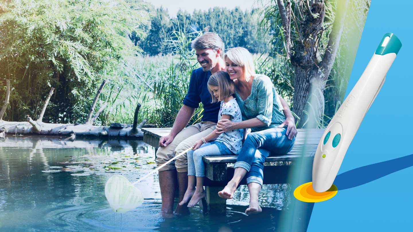 Eine Junge Familie sitzt mit Ihrem Kind an einem See und Angelt