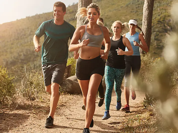 Eine Gruppe von Mensche jogged auf einem Kiesweg in den Bergen.